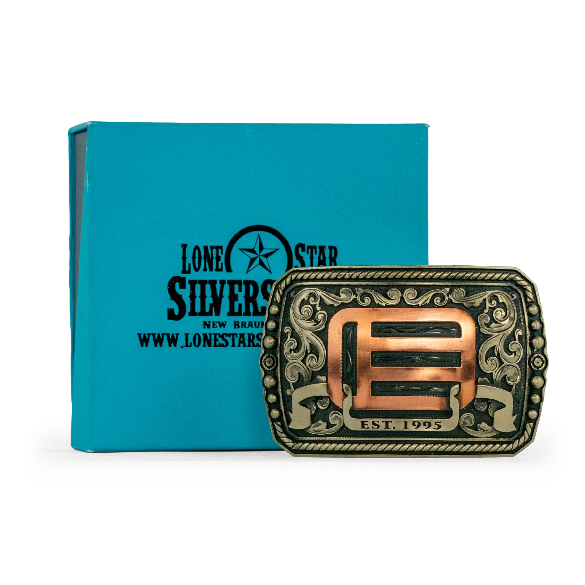An ornate western-style belt buckle with gold-toned metal edges, and copper-toned scrollwork and geometric details, shown alongside its box on a white background.
