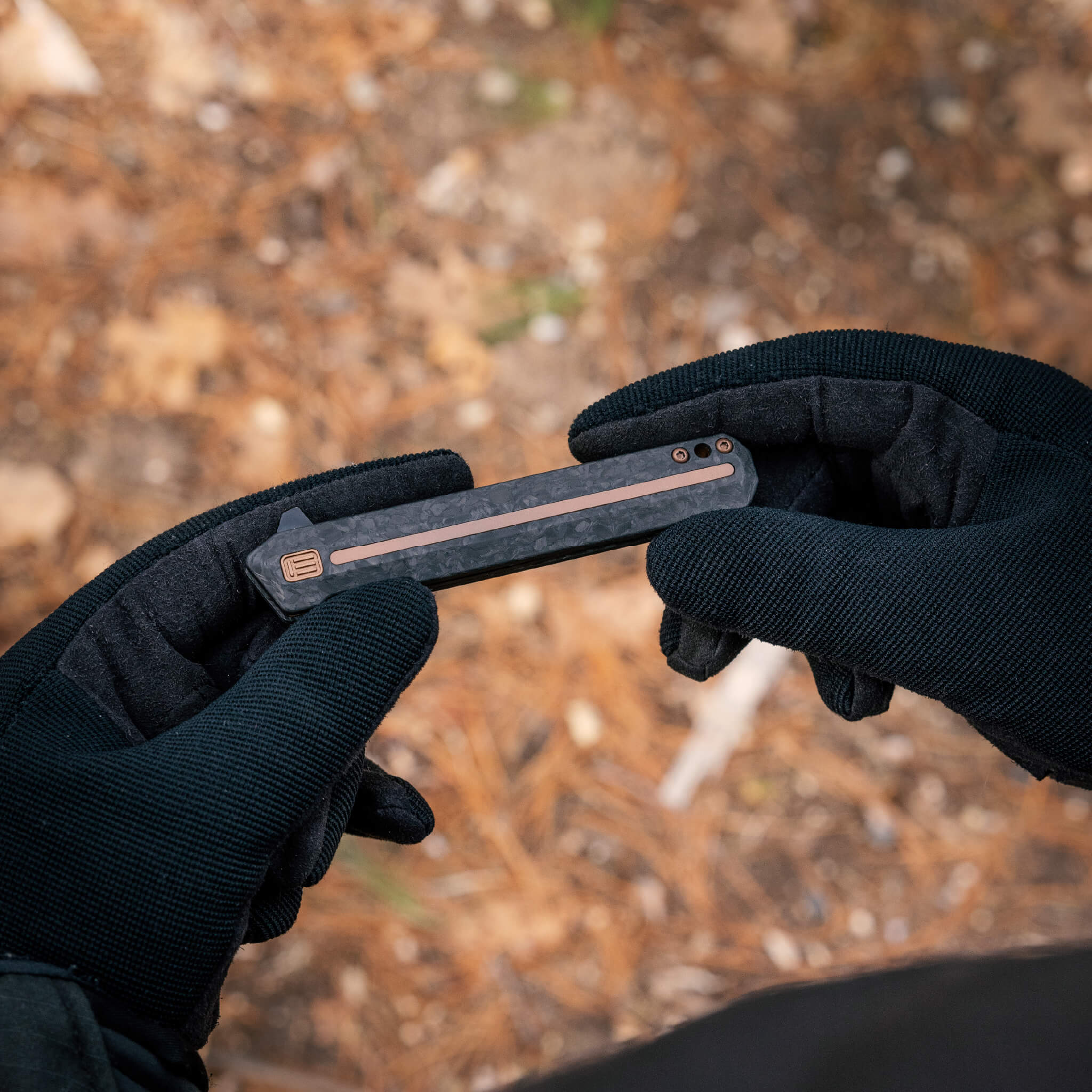 Person holding a folding knife with a blurred natural background