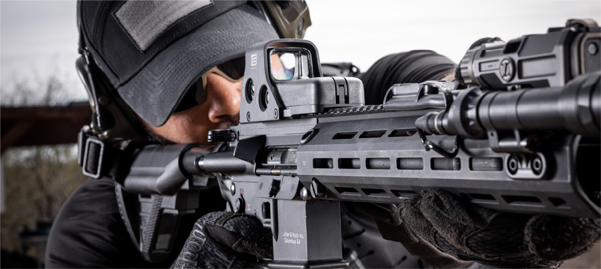 Person wearing tactical gear and holding a rifle with a black EOTECH HWS optic and OGL.