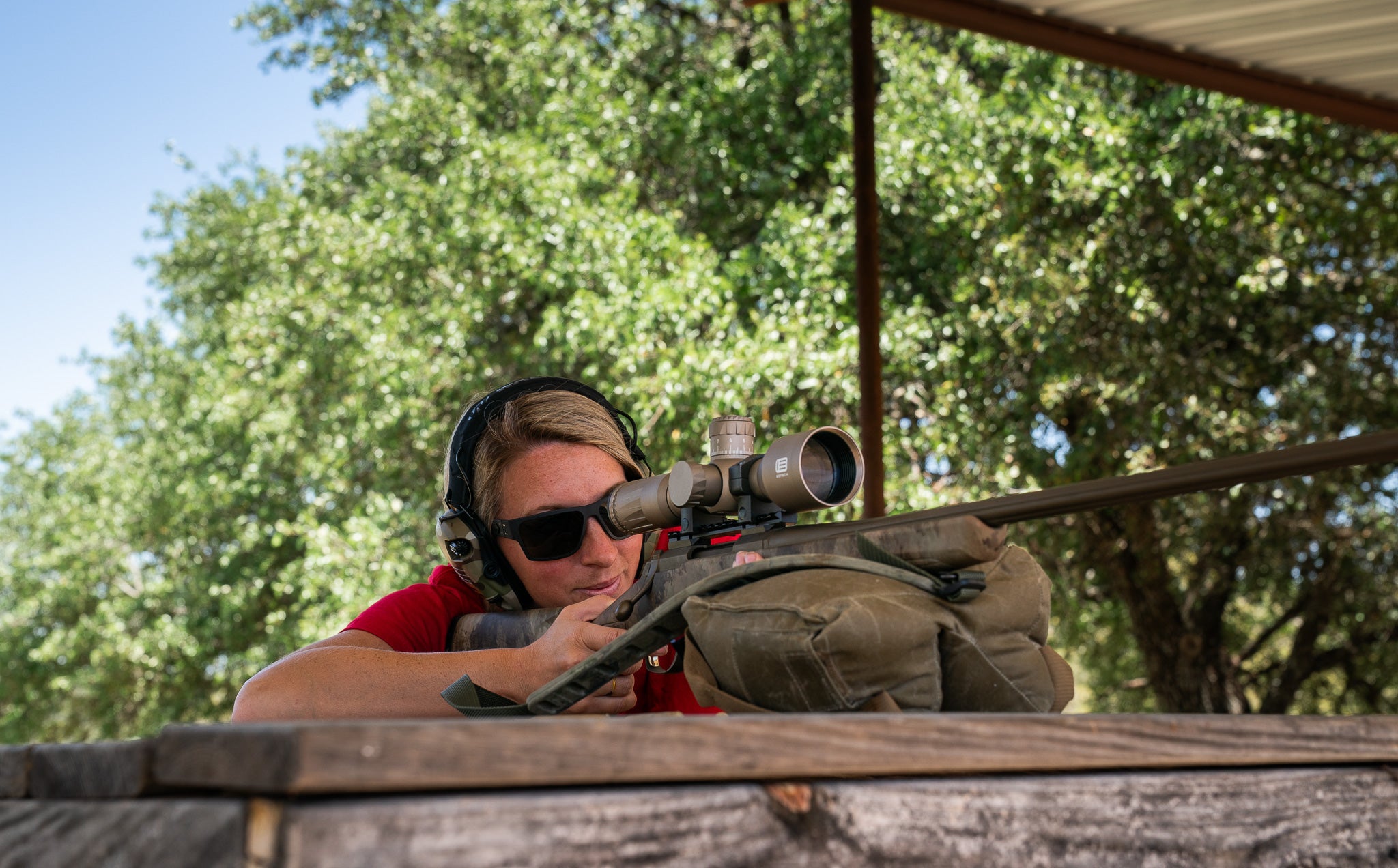 Woman aiming a rifle with a EOTECH Vudu scope outdoors