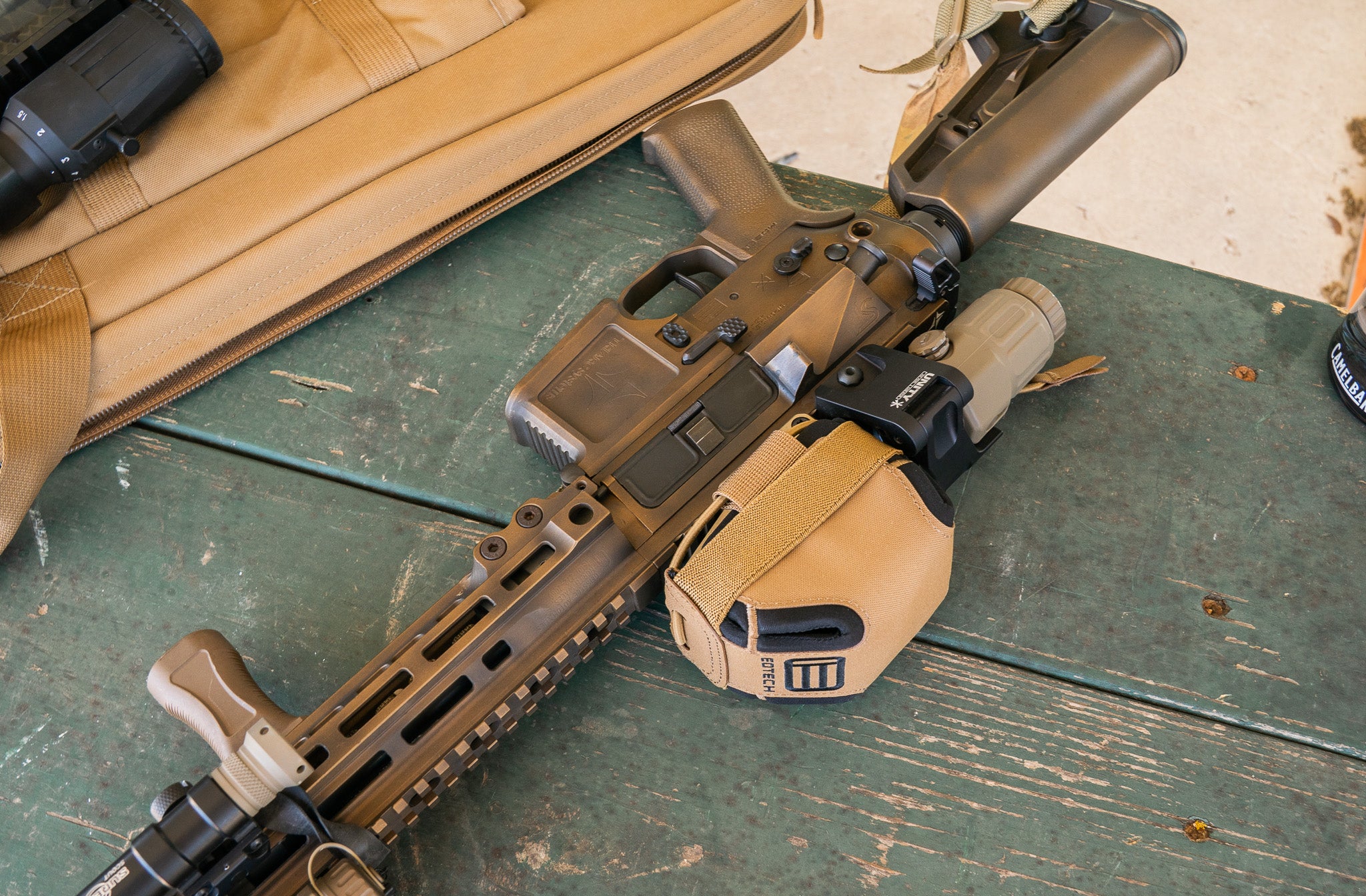 Bronze Rifle with tan scope cover on a green surface