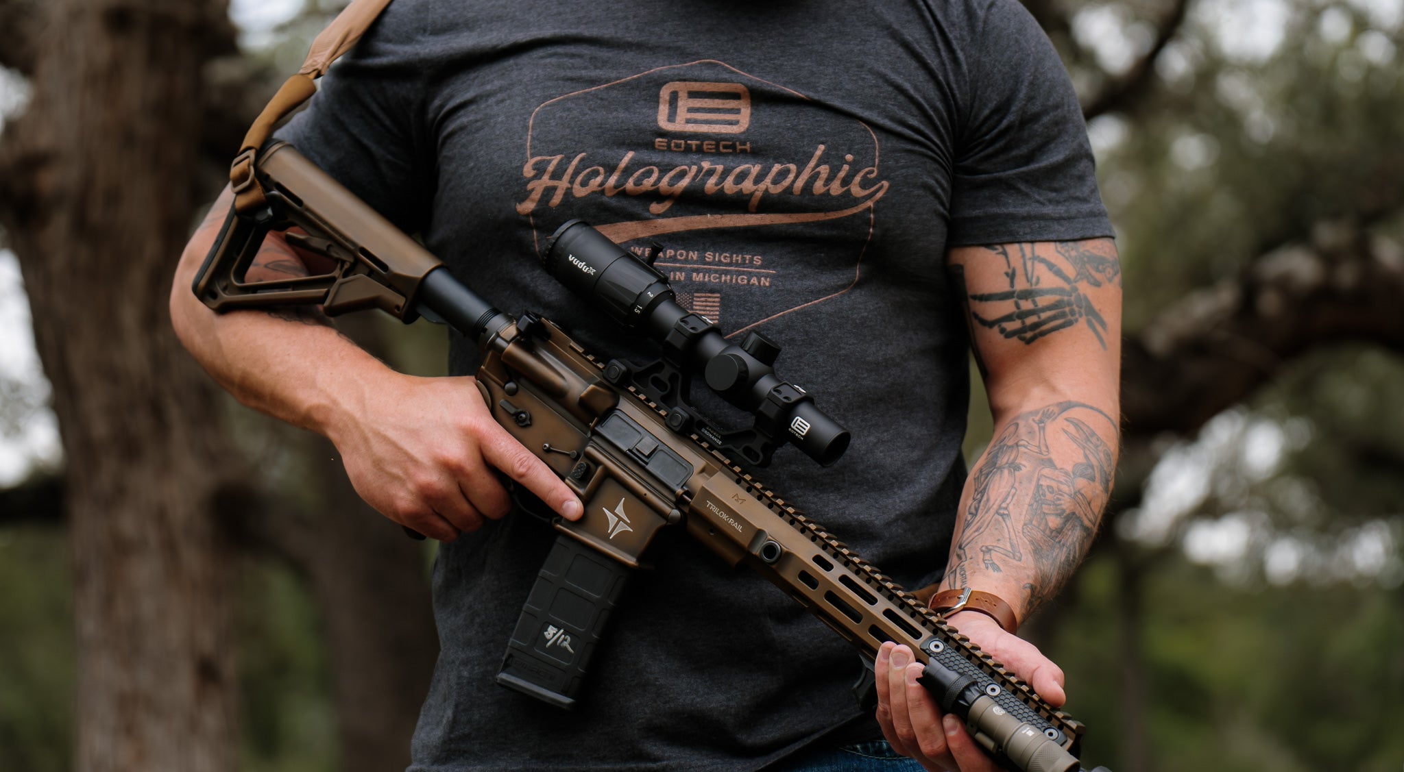 Person holding a rifle with EOTECH Vudu optic with a blurred natural background