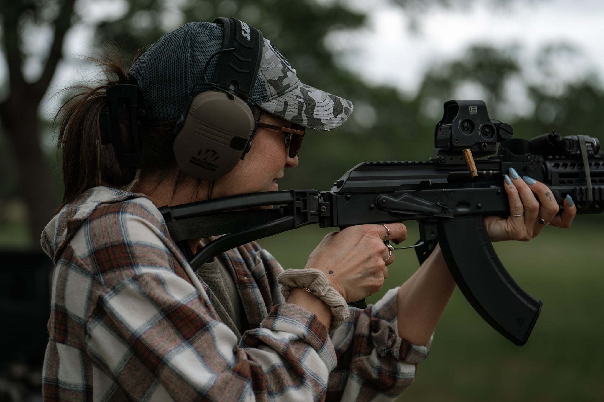 Woman holding a rifle with EOTECH HWS optic in an outdoor setting