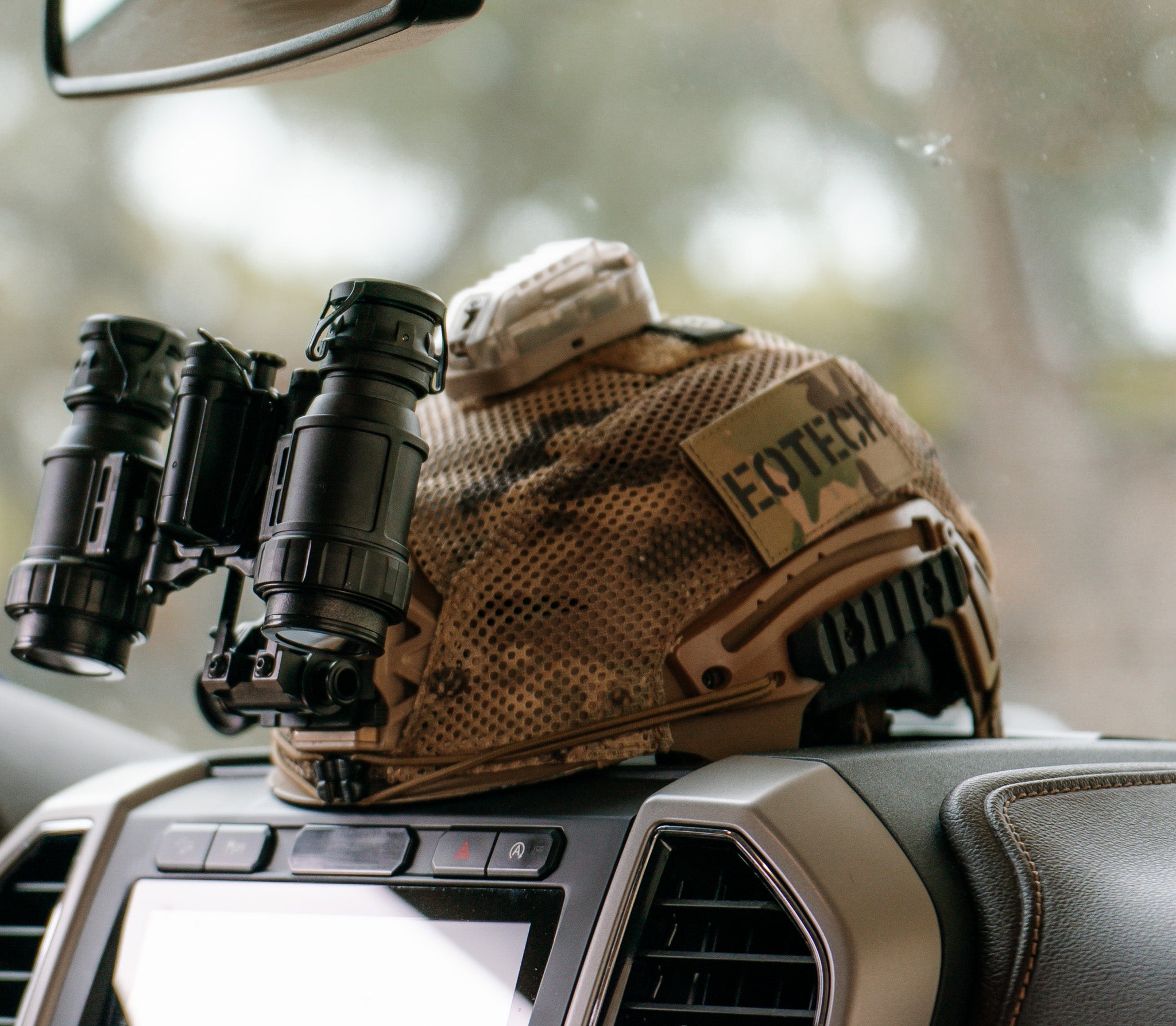 Tactical helmet with EOTECH binoculars on a car dashboard