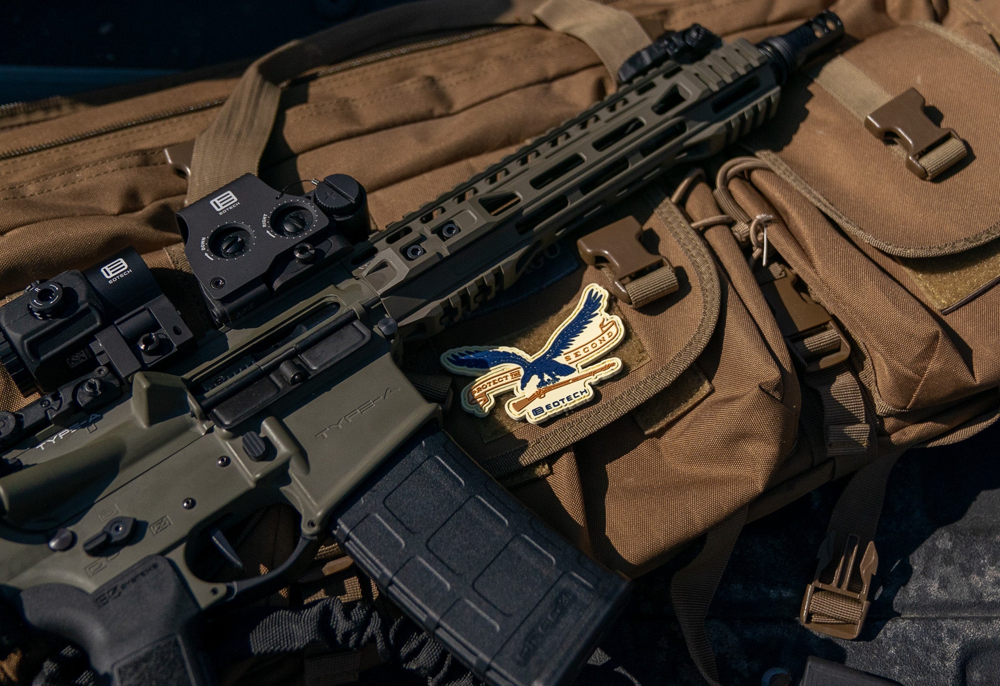 OD Green rifle with EOTECH HWS optic and G43 magnifier on a brown bag with a EOTECH logo.
