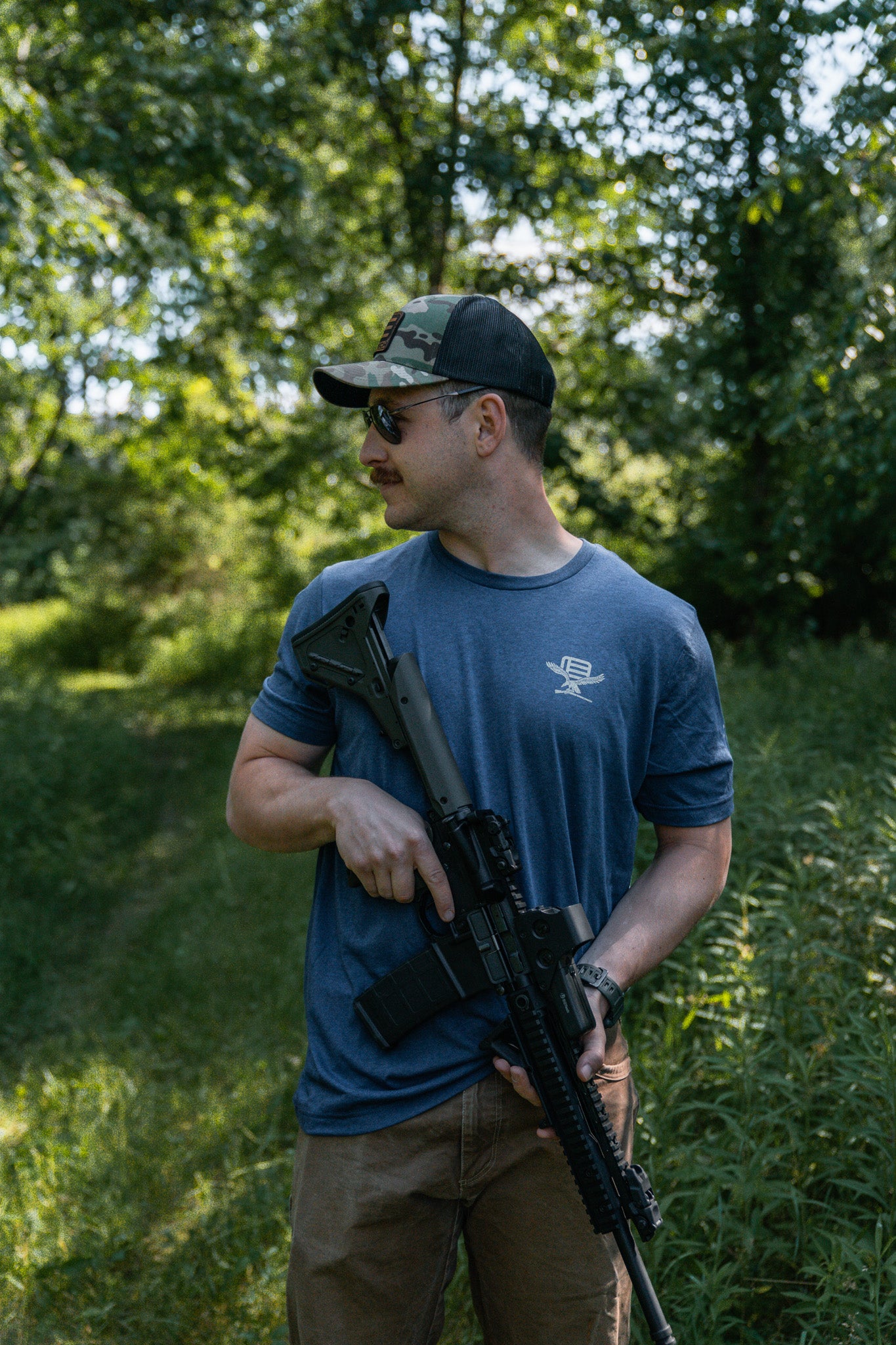Man holding a rifle with EOTECH HWS 5-Series optic in a forested area