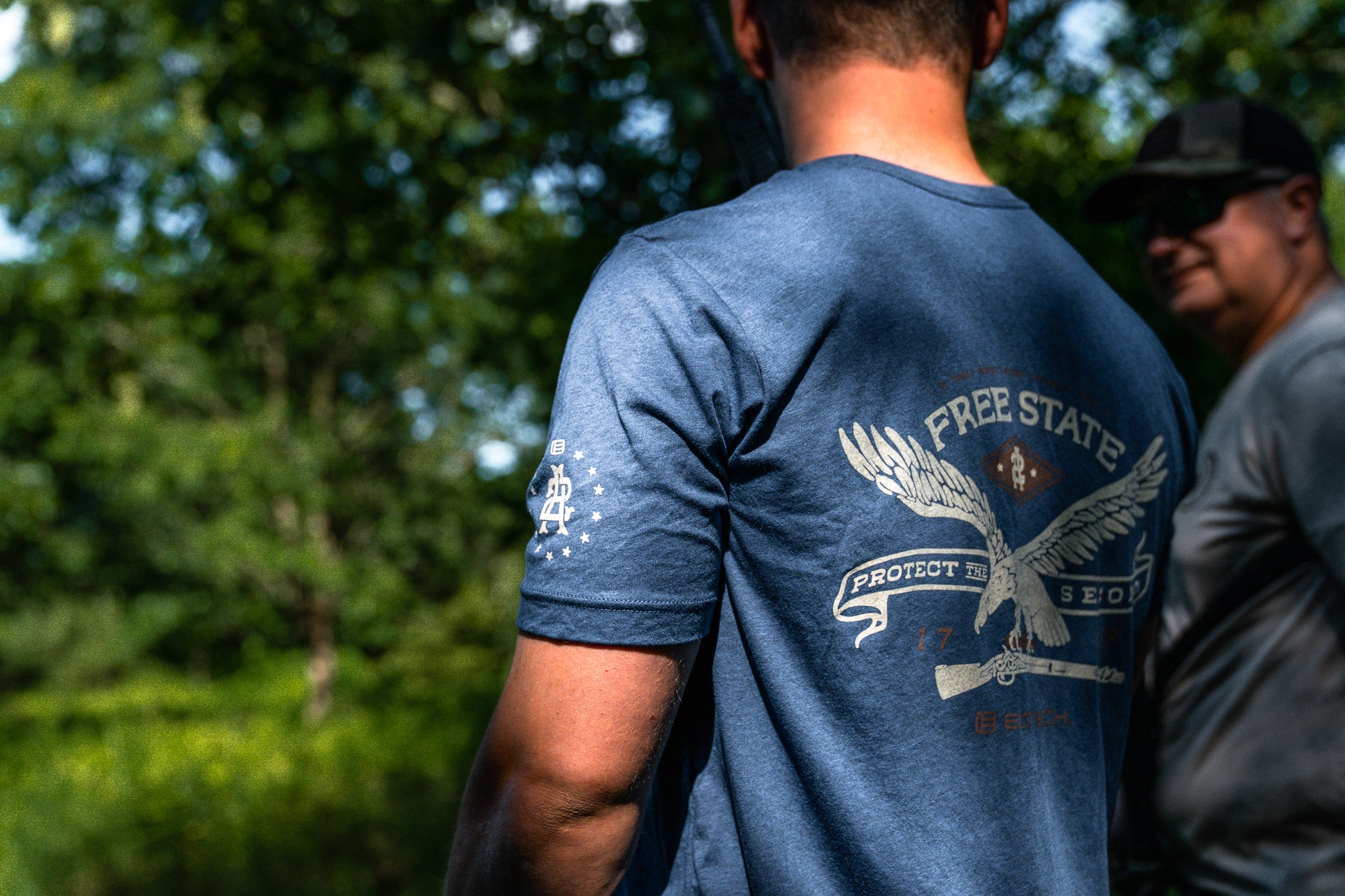 Person wearing a blue Protect The Second t-shirt with a graphic design outdoors