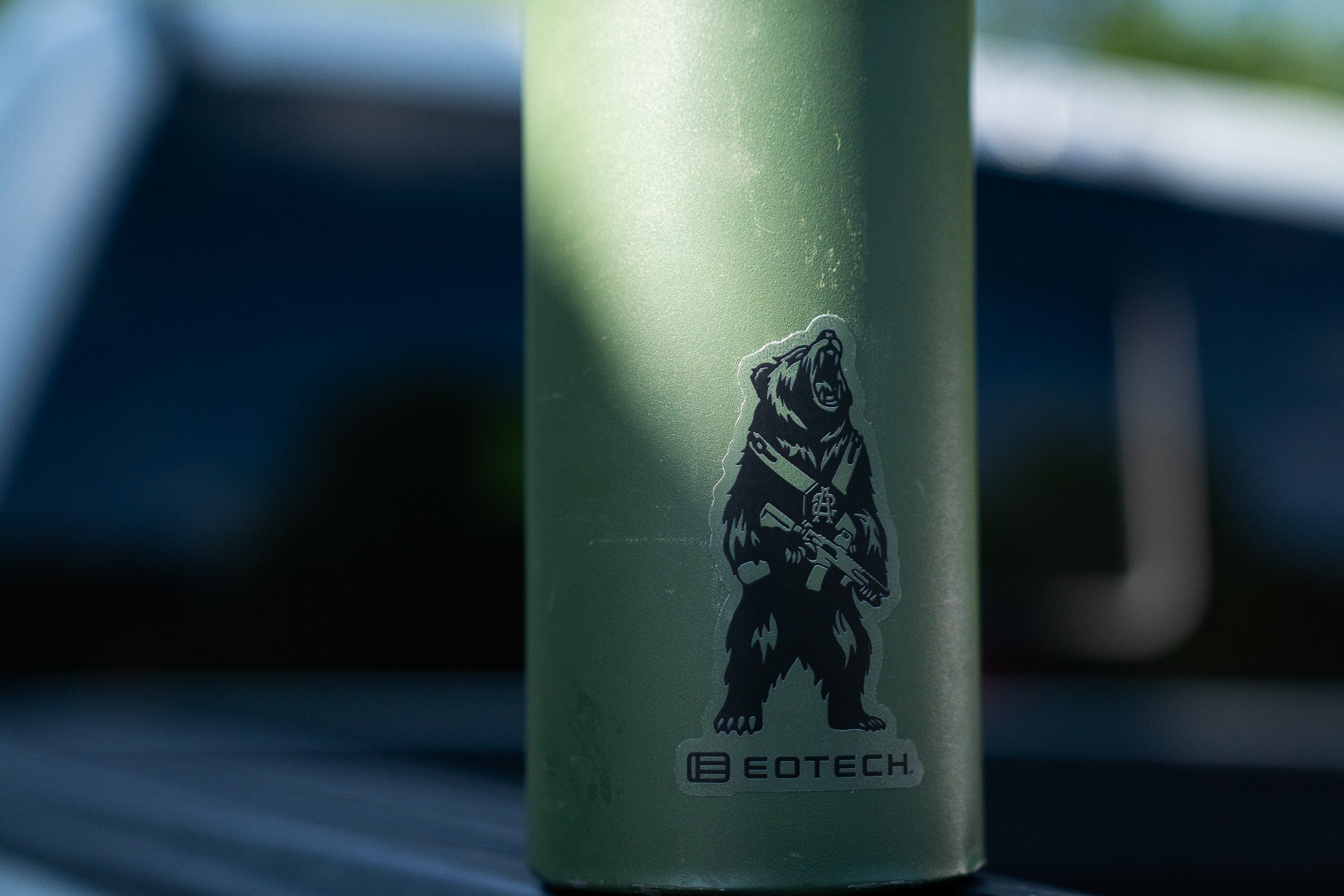 Green water bottle with a bear graphic and EOTECH branding on a blurred background