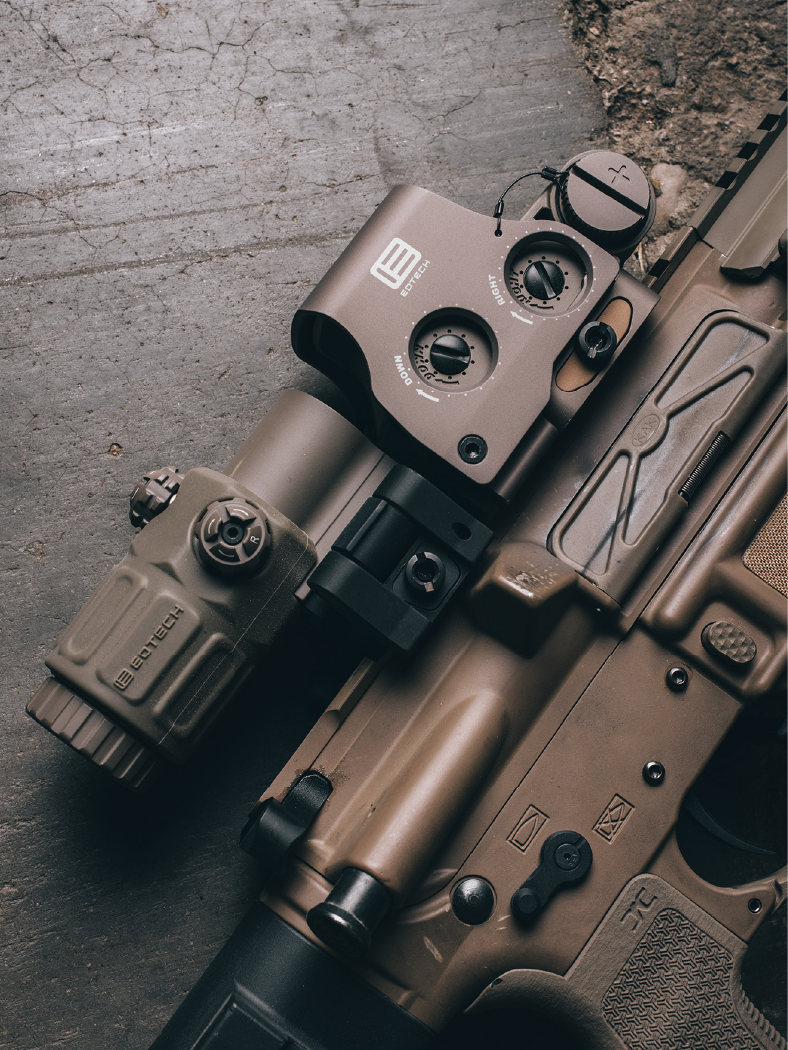 Tan rifle with EOTECH HWS optic and magnifier on a textured surface
