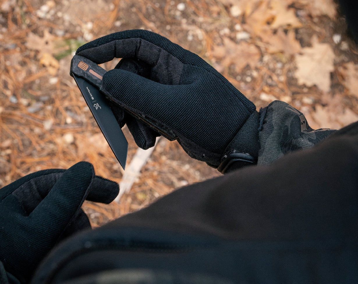 Person wearing black gloves holding a EOTECH knife with a natural background