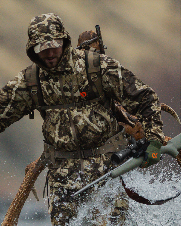 Person in camouflage hunting gear with a rifle and EOTECH Vudu black scope in water