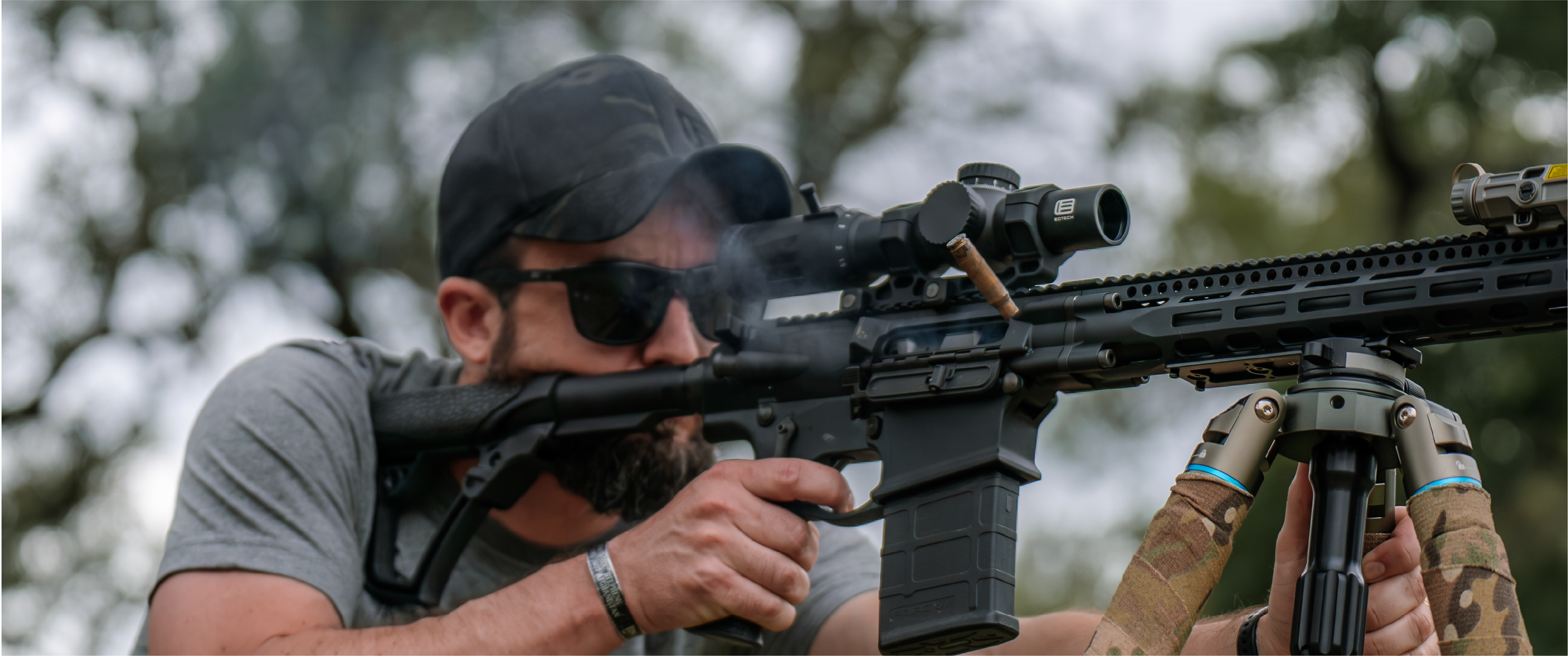 Man holding a rifle with a EOTECH Vudu scope in an outdoor setting