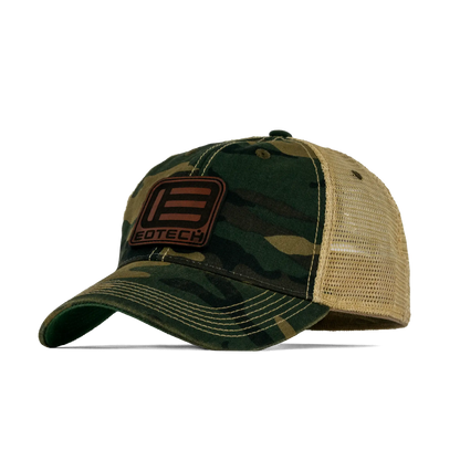 A camouflage trucker hat with a tan mesh back and a brown leather patch on the front that reads EOTECH.