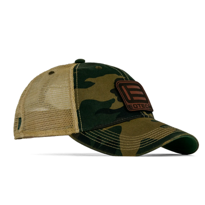 A camouflage trucker hat with tan mesh back panels and a brown leather patch on the front displaying the EDTOGA brand logo.