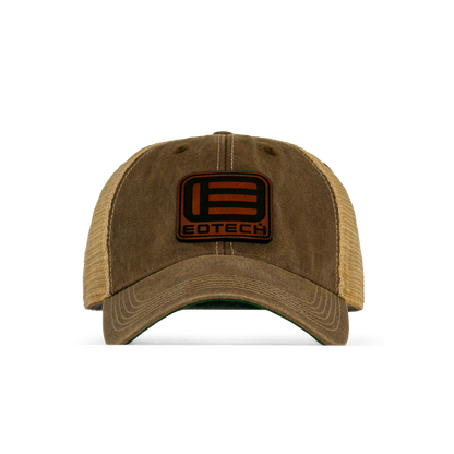 A trucker-style baseball cap with a washed brown front panel and curved brim, tan mesh back, and a black rectangular patch on the front featuring a stylized 'E' logo and the word 'EOTECH'.