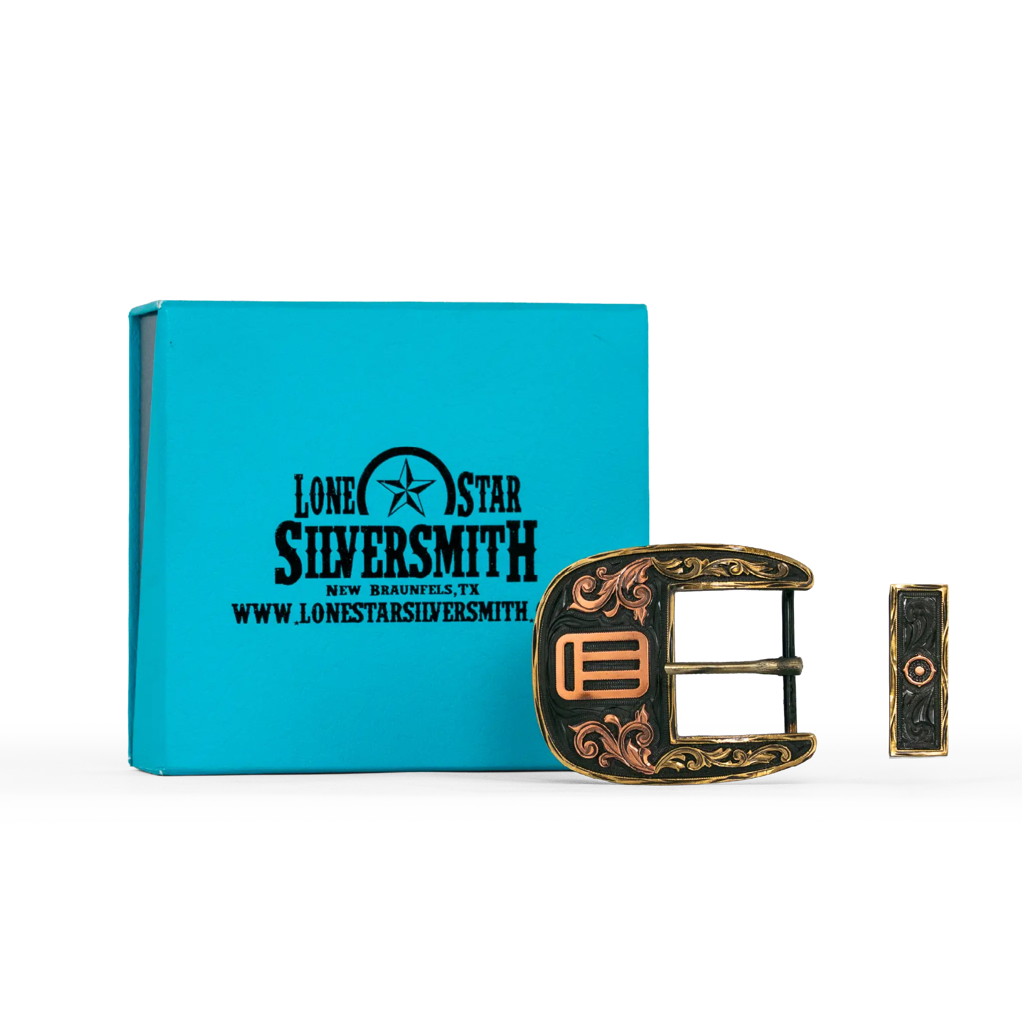 A decorative silver smith buckle with ornate filigree detailing, shown next to its turquoise branded presentation box on a white background.