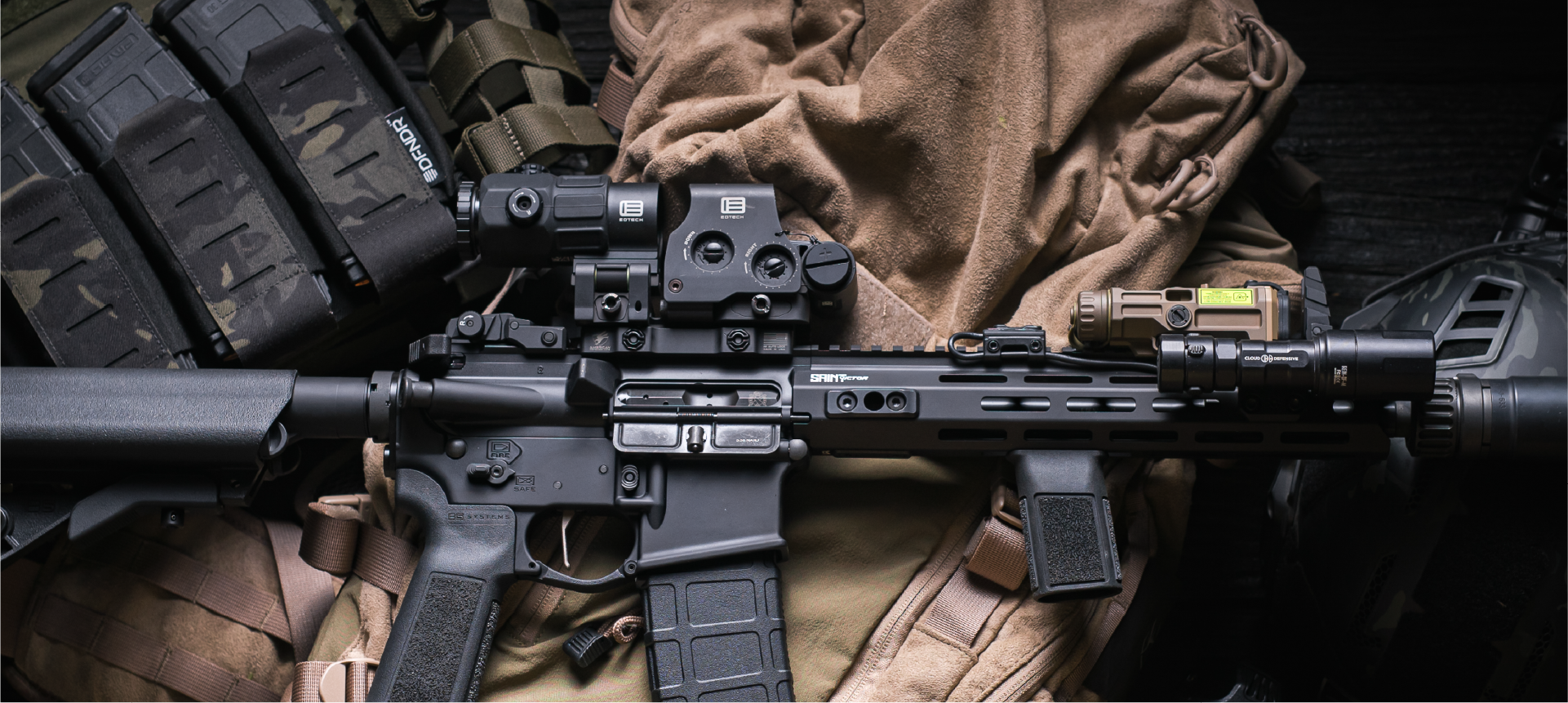 Rifles with black EOTECH HWS optic and magnifier on tan case