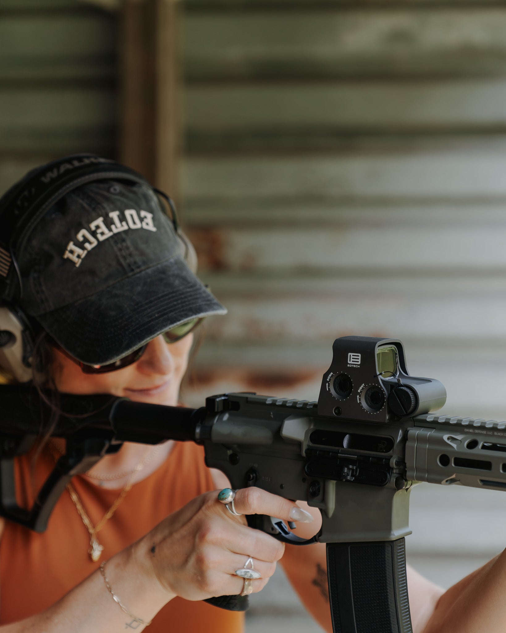 Person wearing a black cap with upside down EOTECH and sunglasses with a blurred background