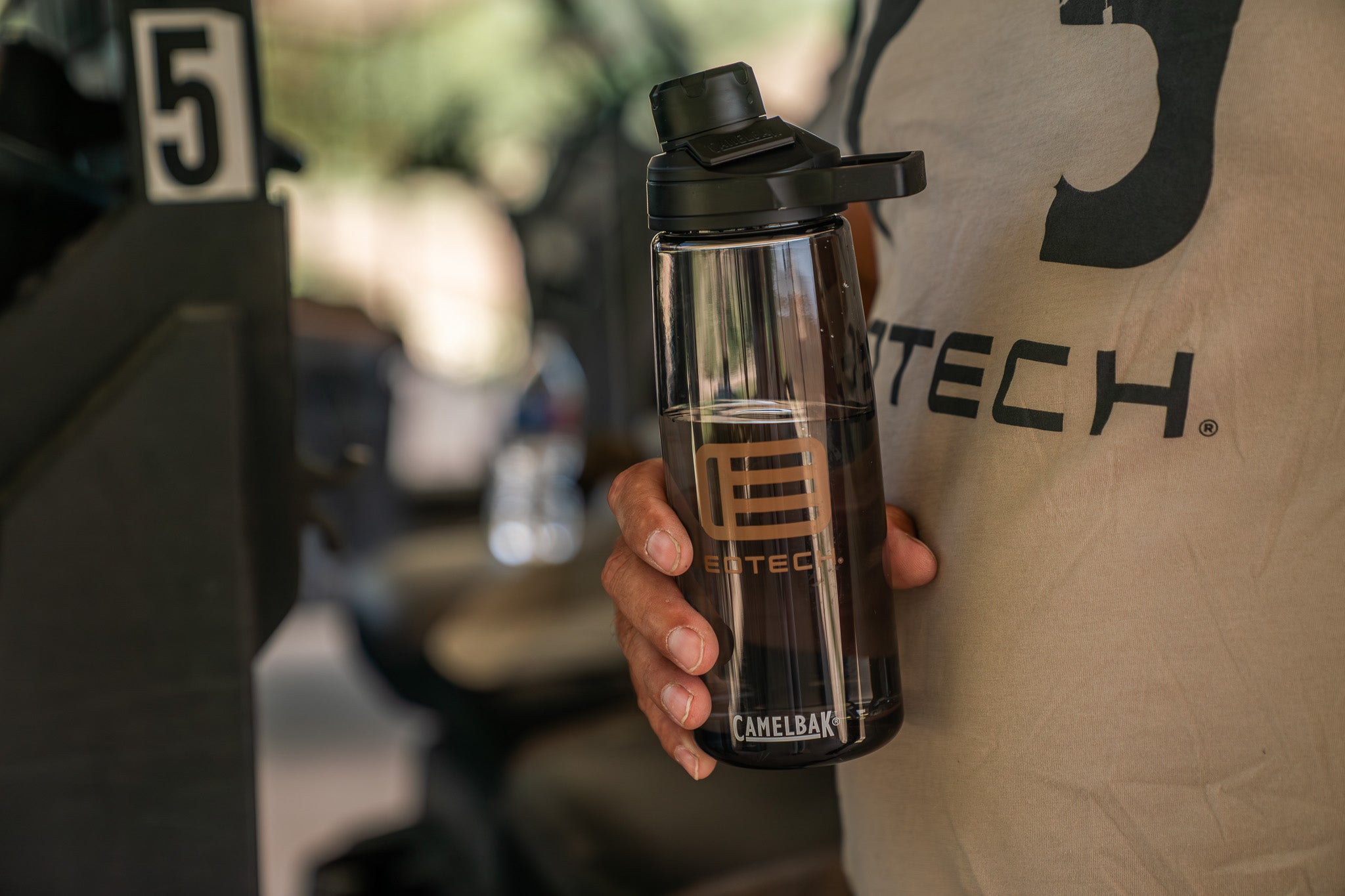 Hand holding a EOTECH water bottle with blurred background. 