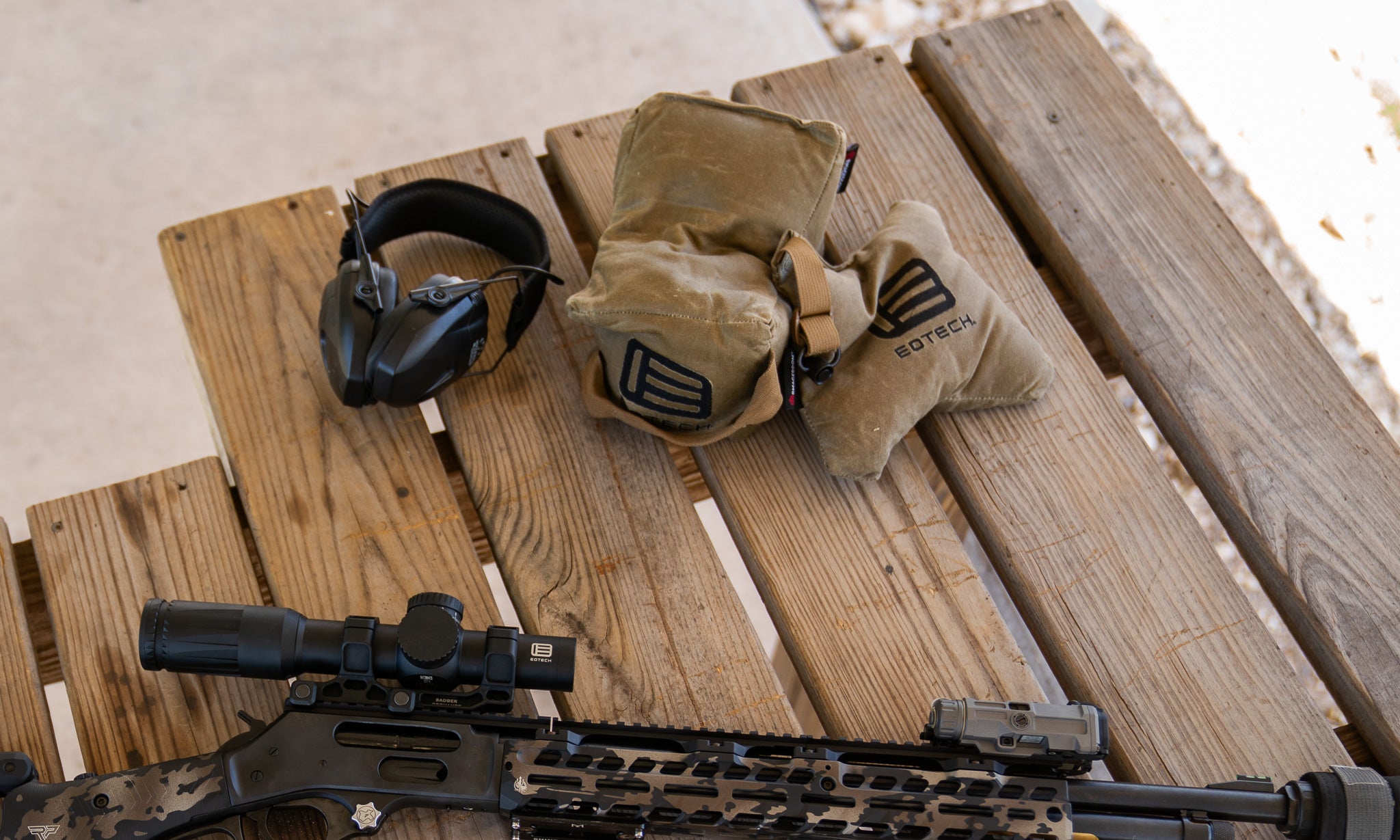 Vudu Riflescope, ear protection, and tactical pouches on a wooden surface