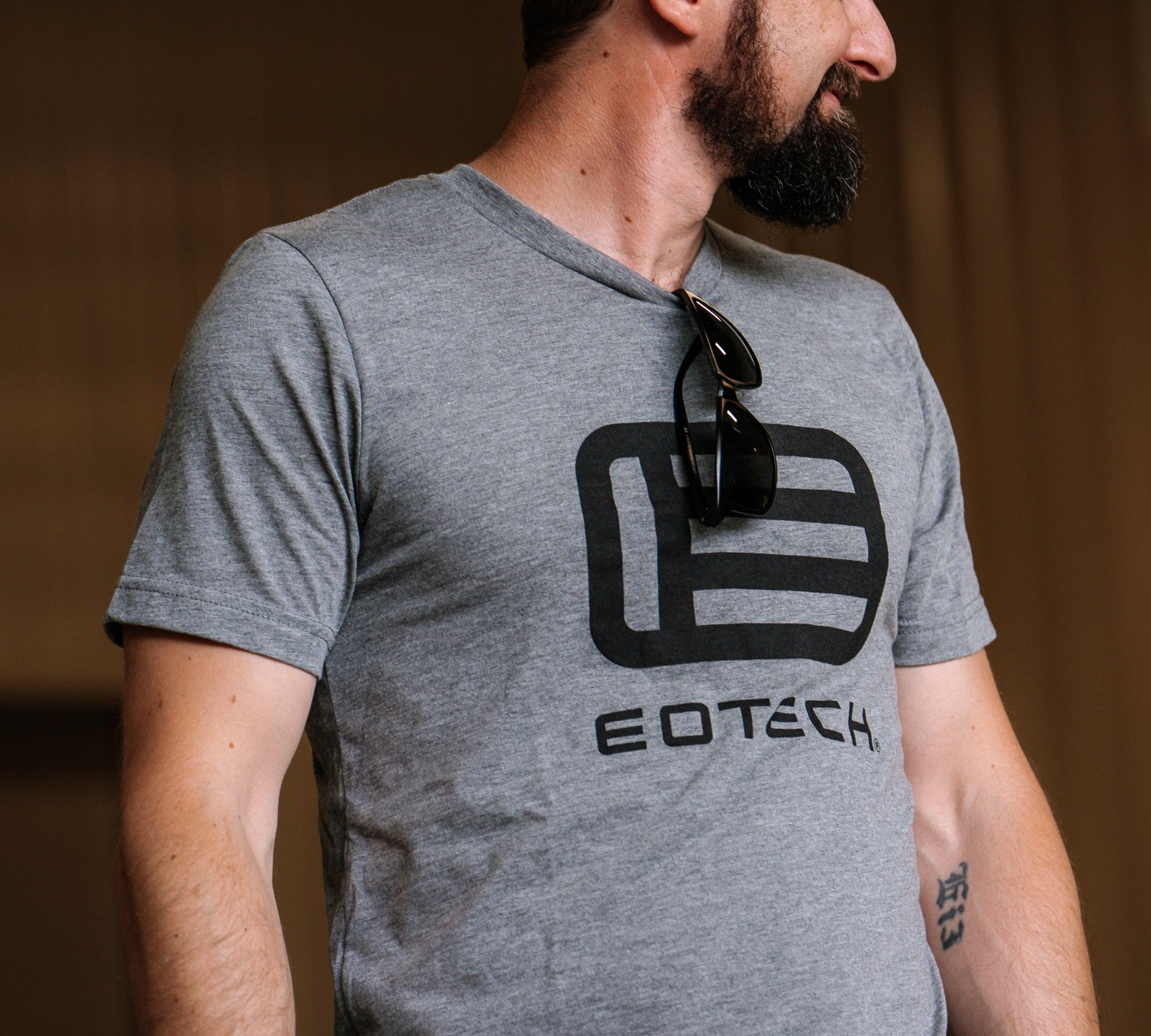 Man wearing a gray t-shirt with EOTECH logo and sunglasses on chest
