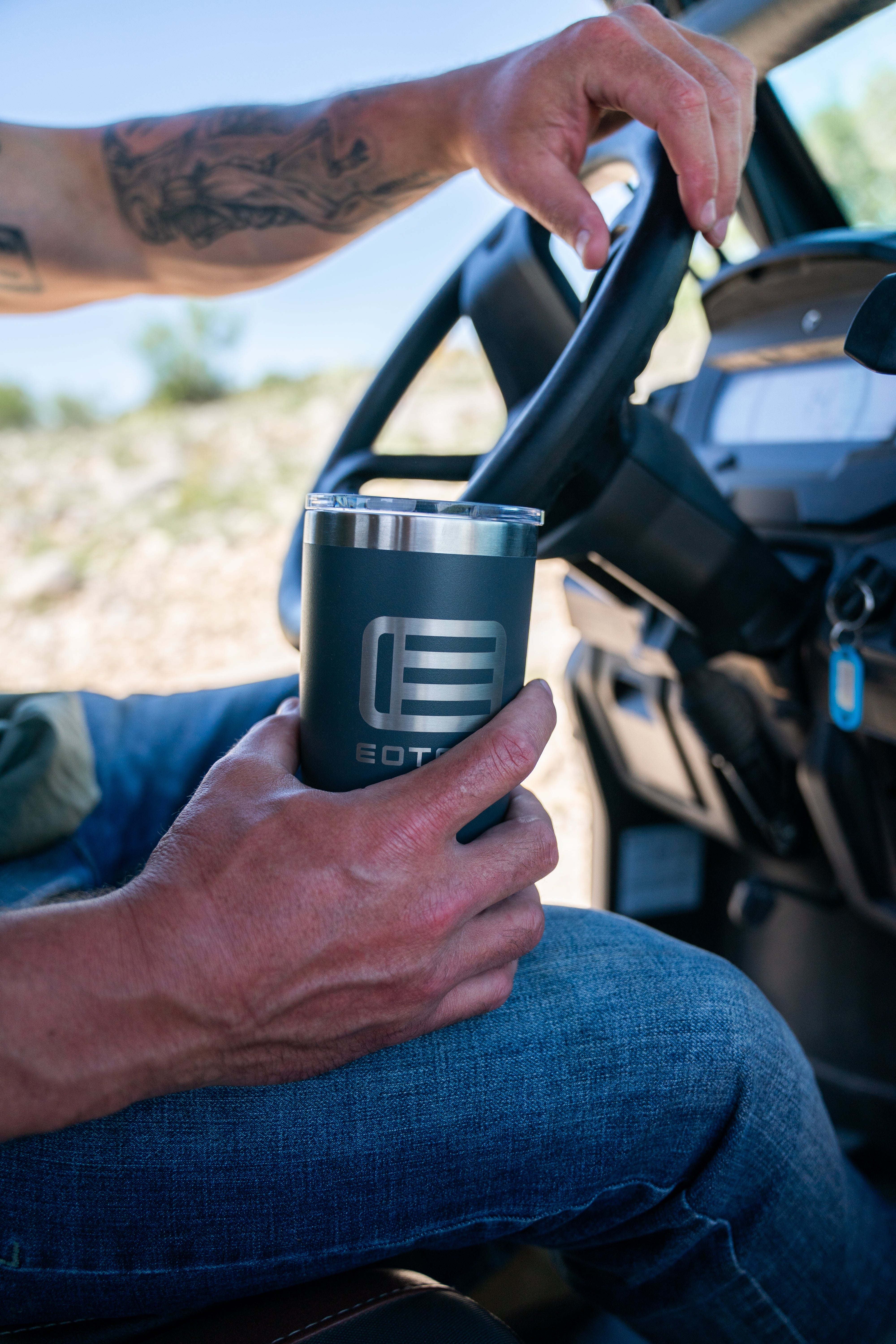 Man holding a black EOTECH tumbler in a vehicle