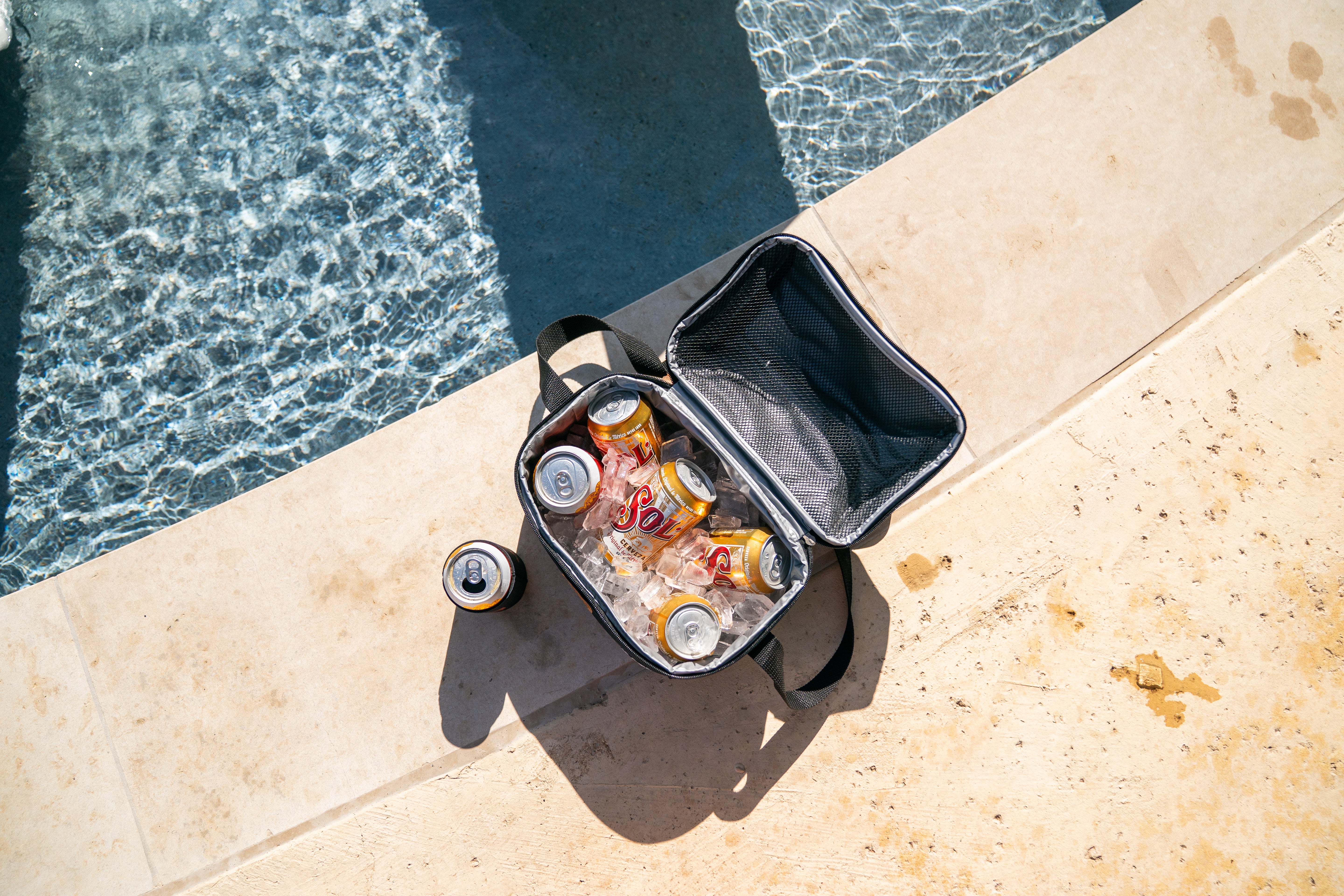 Black insulated cooler bag with drinks by a poolside