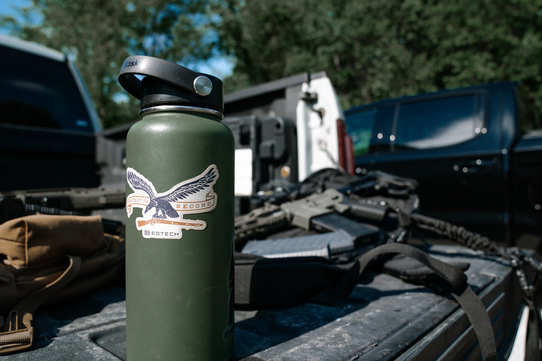 Green water bottle with a EOTECH logo on a vehicle's open trunk