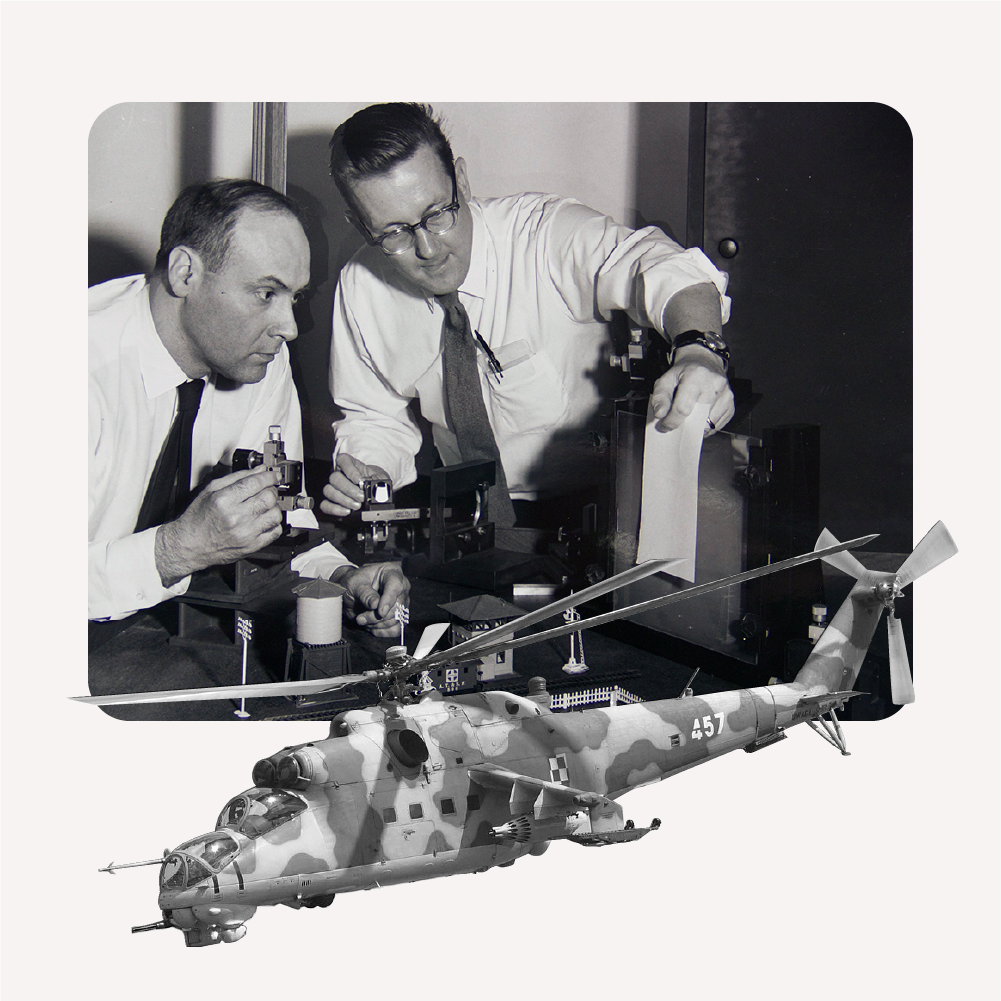 Two men examining a model helicopter with a camouflage design.