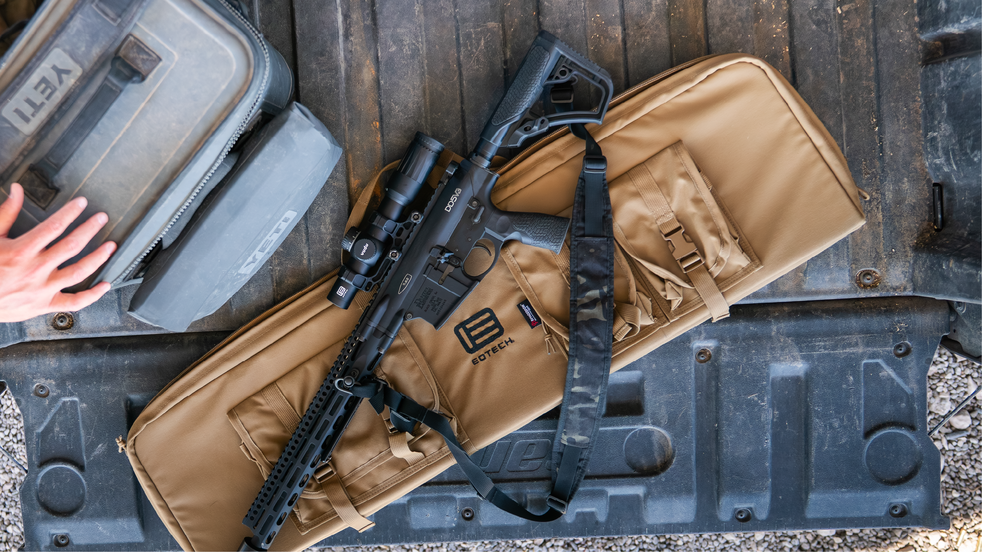 Rifle on a EOTCH brown carrying case with a visible brand logo, placed on a textured surface.