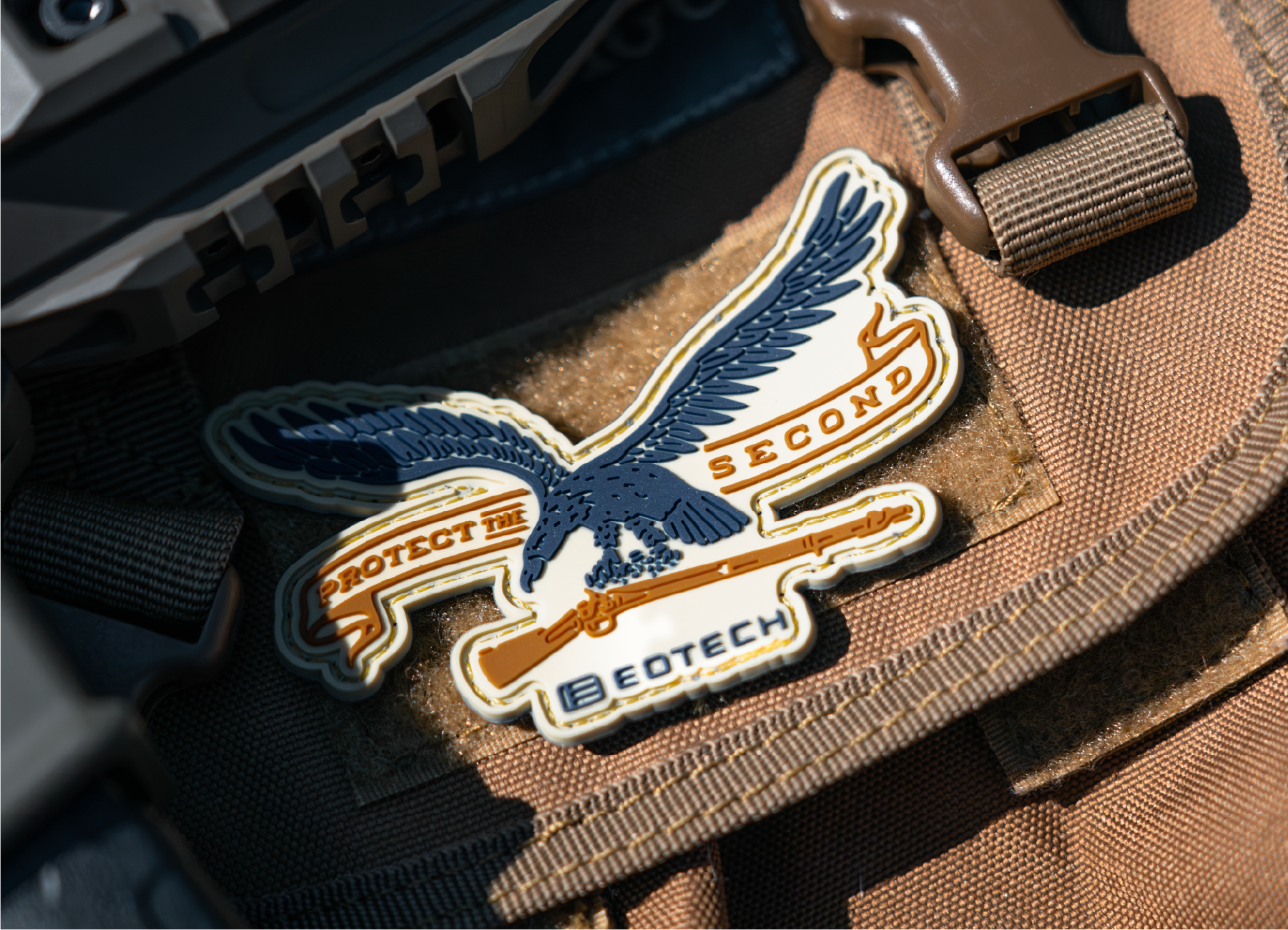 Patch with an eagle design and Protect the Second  and EOTECH logo  on a brown tactical bag