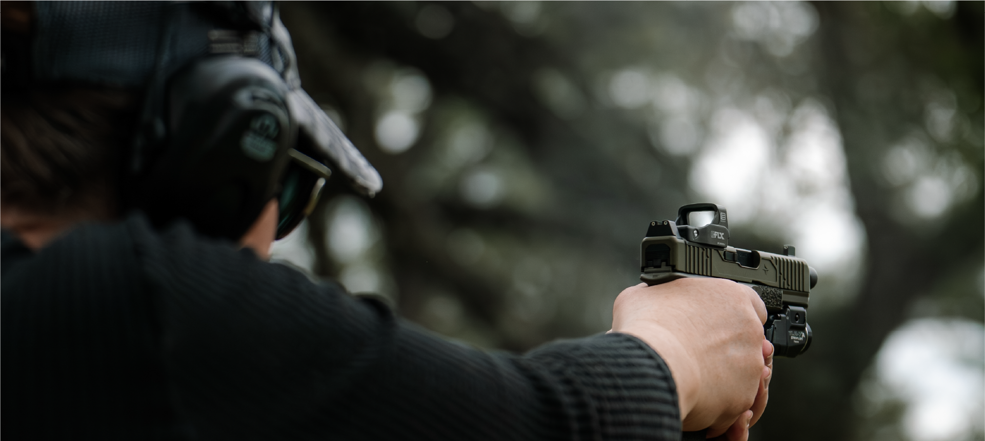 Person holding a handgun with a EOTECH EFLX red dot optic outdoors