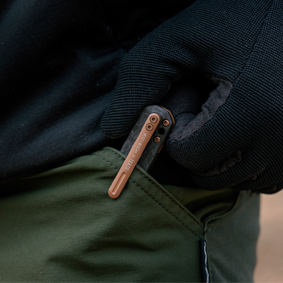 EOTECH knife attached to a dark jacket pocket with a blurred background