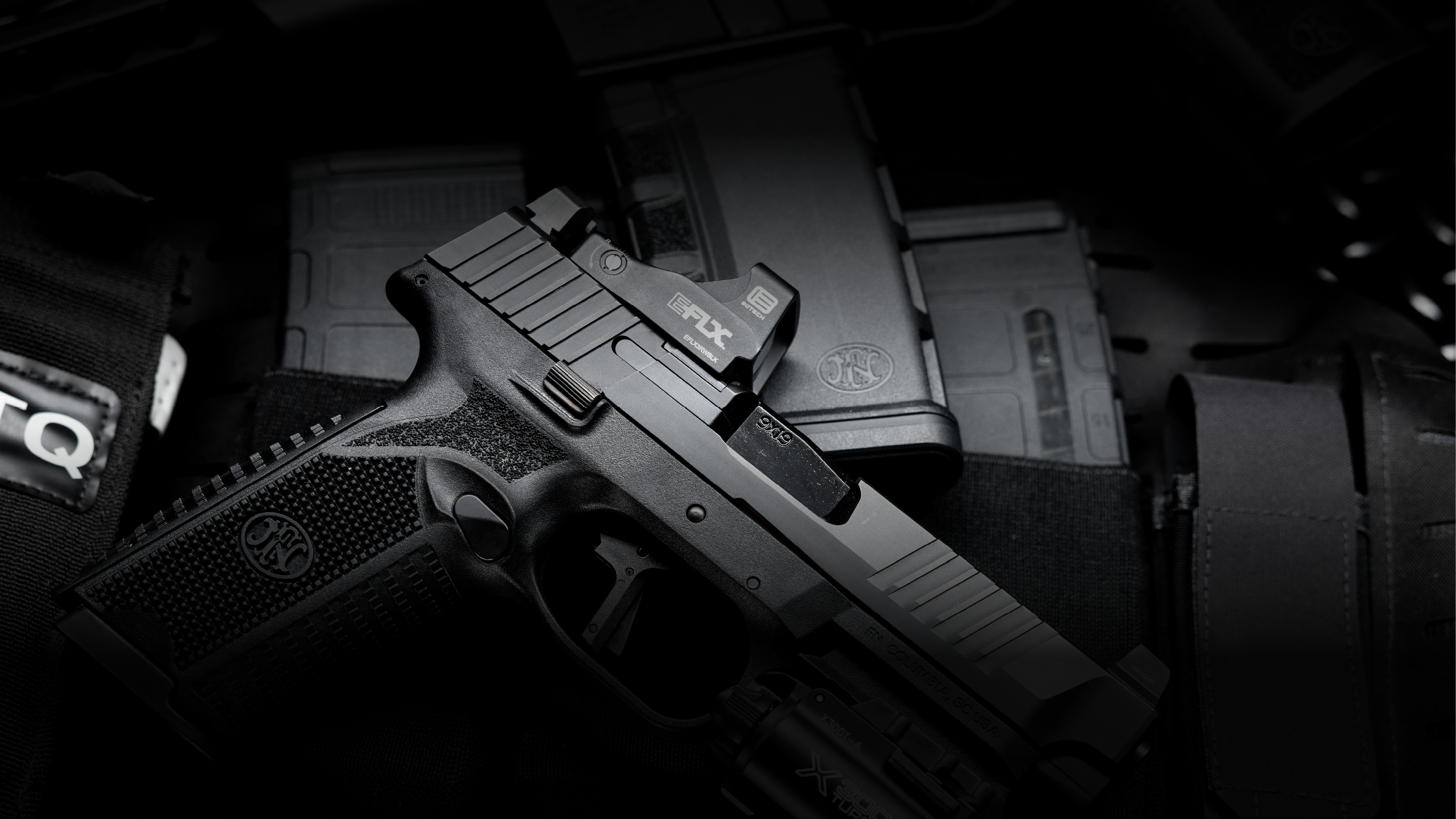 Black handgun with EOTECH EFLX red dot optic on a dark background