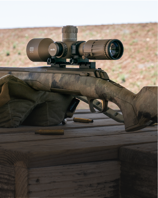 EOTECH Vudu tan Riflescope on  a rifle with camouflage pattern, placed on a wooden surface.