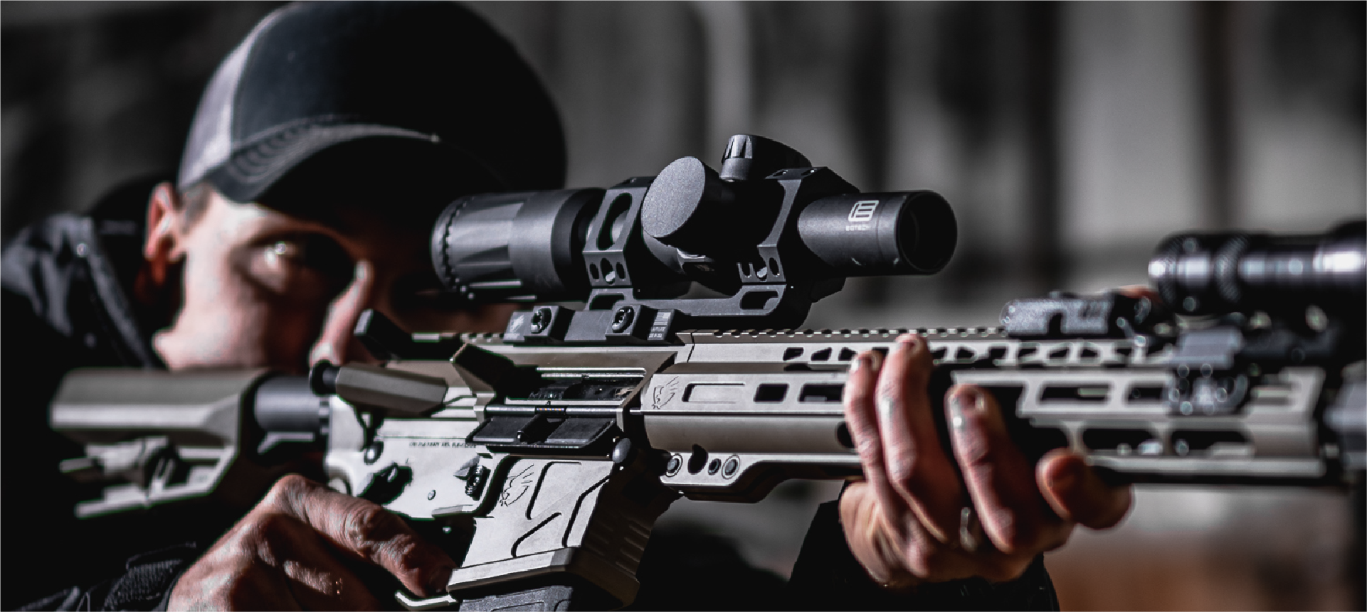 Person holding a rifle with a EOTECH Vudu black scope, blurred background
