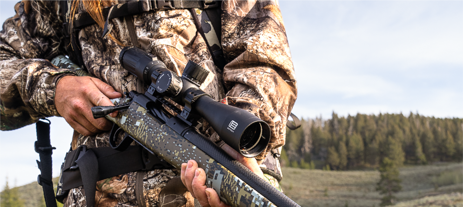 Hunter in camouflage holding a rifle with a EOTECH Vudu black scope in a forest setting
