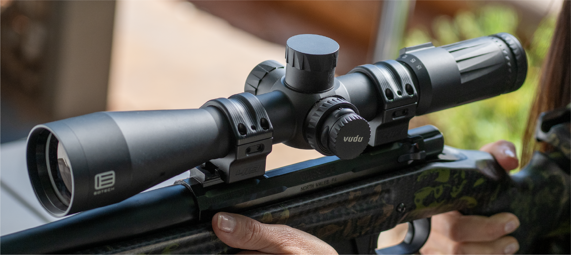 Rifle with a EOTECH Vudu black scope being held, blurred background