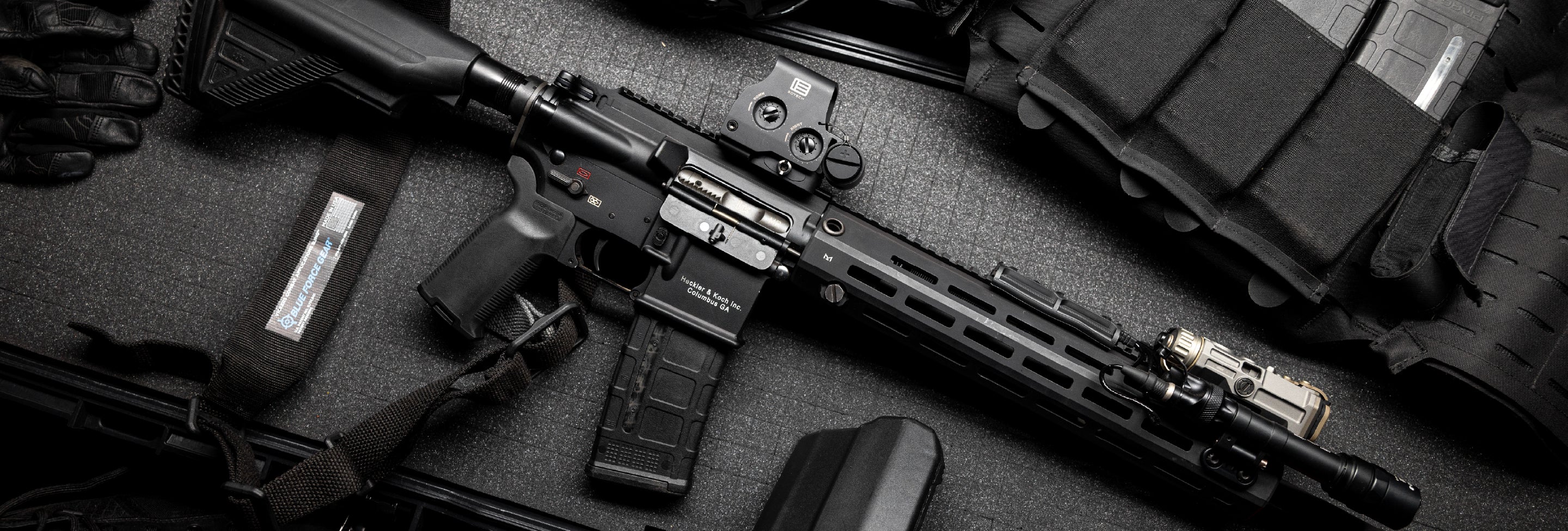 Black rifle with EOTECH HWS optic and accessories on a dark surface