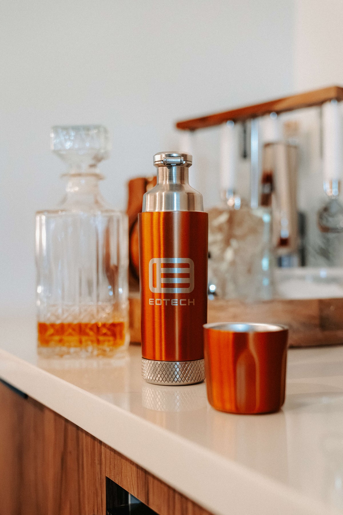 Copper flask with EOTECH logo, shallow depth of field, on countertop with bar materials in the background