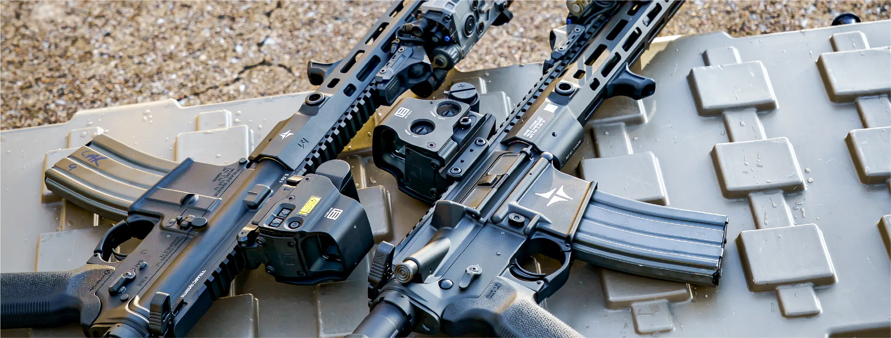 Two rifles with EOTECH Optics on a textured surface 