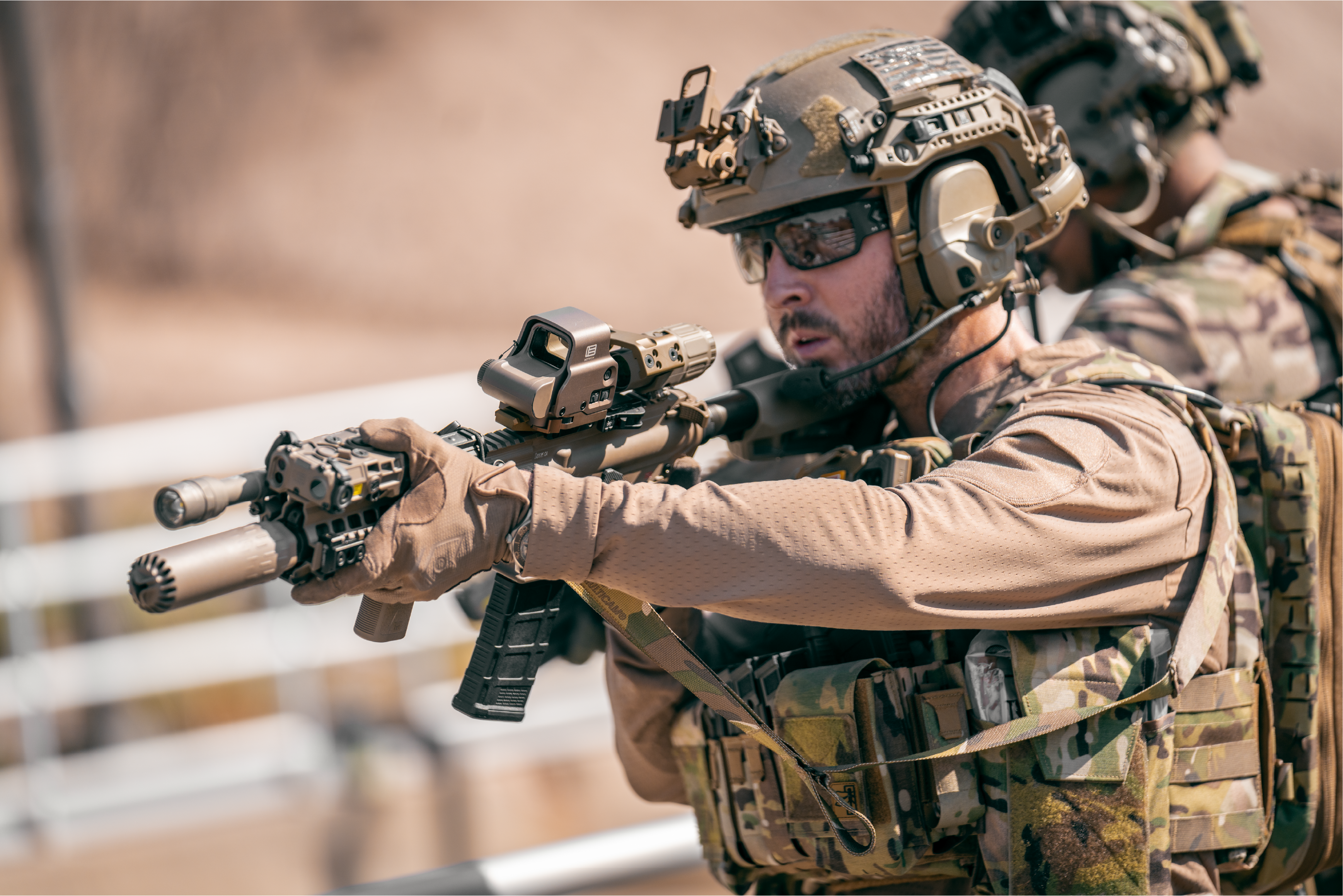 Soldier in tactical gear with a rifle adn tan EOTECH HWS optic and magnifier in a desert setting