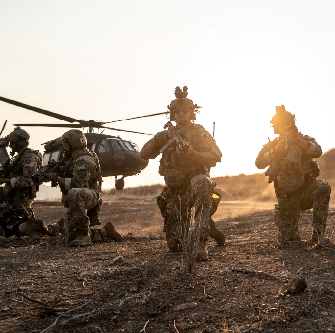 Soldiers in military gear holding EOTECH HWS and Vudu optics with a helicopter in the background