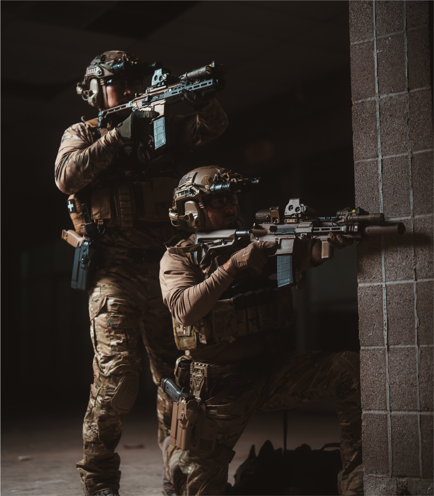Two soldiers in tactical gear holding  rifles with EOTECH HWS optics, magnifiers and OGL in a dark setting.