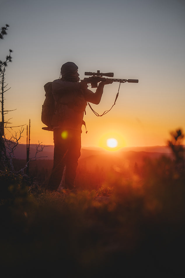 Person with a rifle and EOTECH Vudu scope at sunset in a natural setting