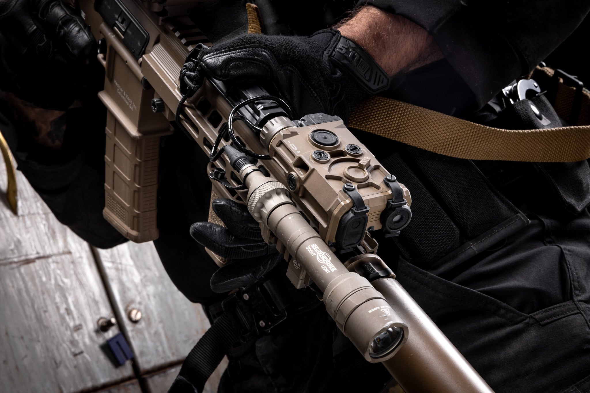 Close-up of a person holding a rifle with EOTECH Tan OGL and dark background