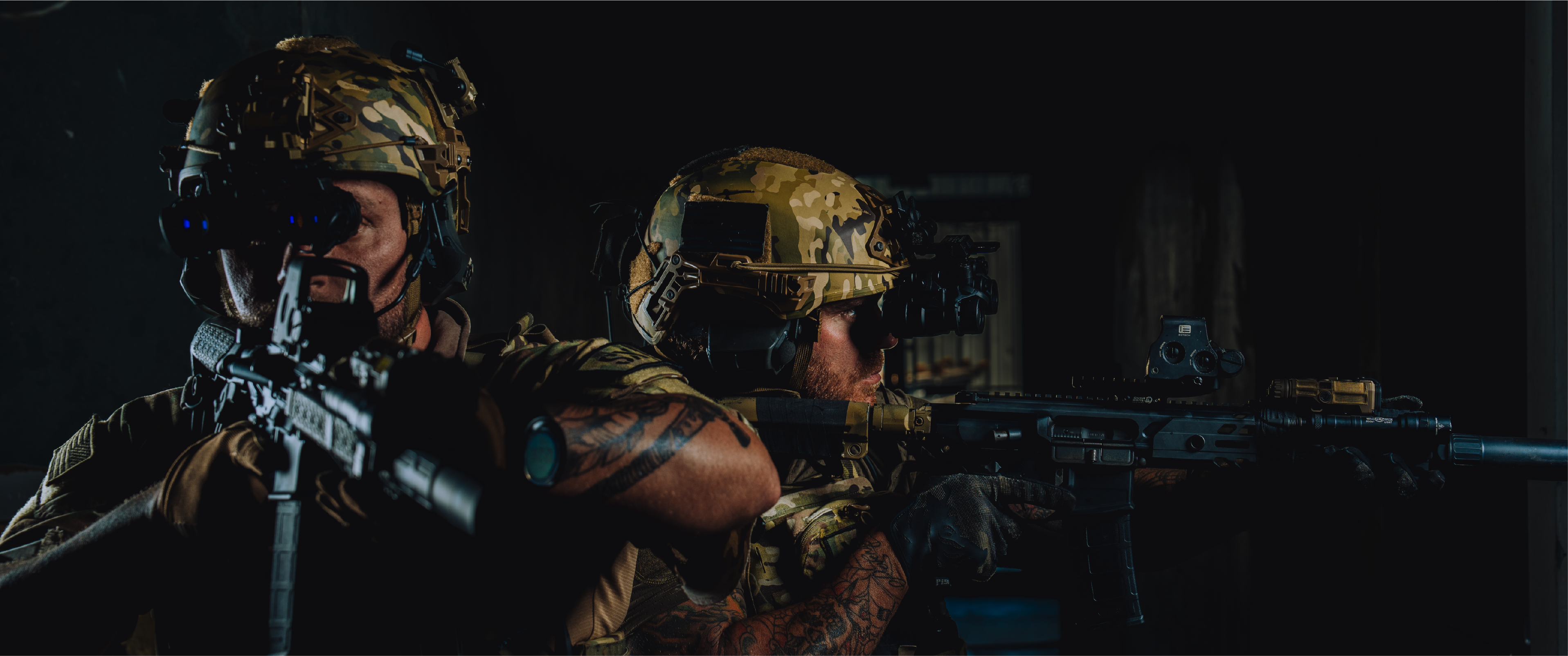 Two soldiers in EOTECH binos  holding rifles with HWS optics and OGL in a dark setting